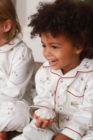 Two children in matching pajamas sitting together, one holding a donut.