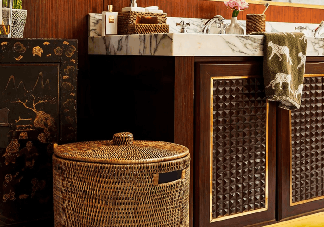 Handwoven Luxe Washing Hamper with its lid on, standing on a marble bathroom floor beside a basin unit