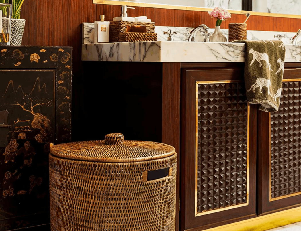Handwoven Luxe Washing Hamper with its lid on, standing on a marble bathroom floor beside a basin unit
