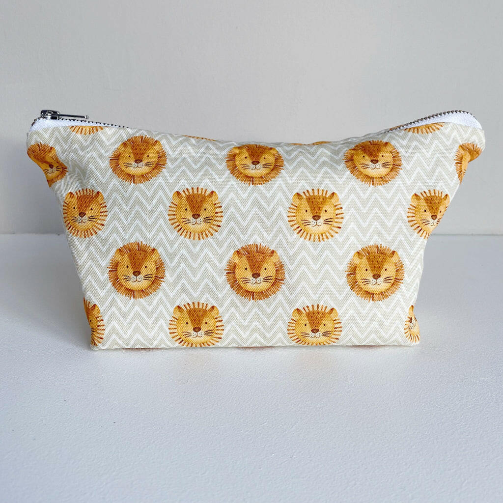 Nappy wallet in Leo lion print, front view of the zipped pouch with lion faces on a cream zigzag pattern