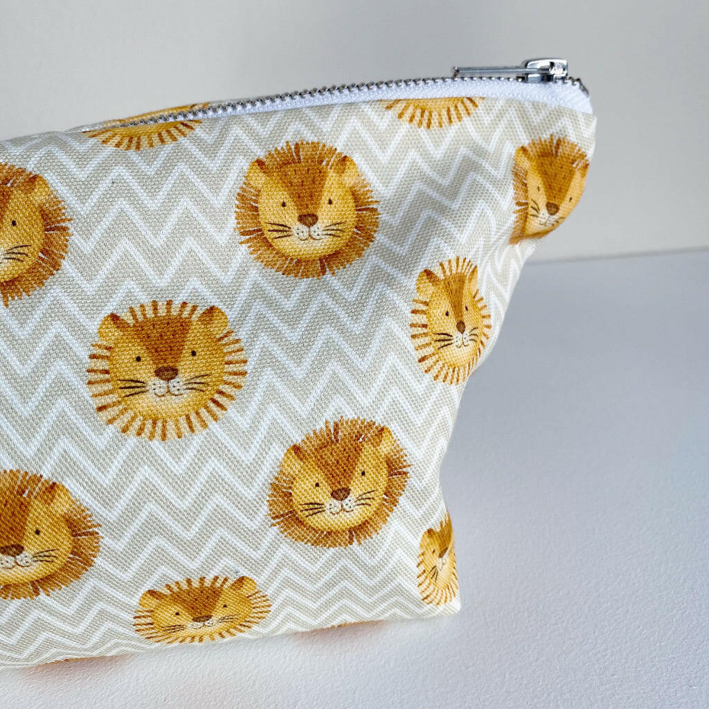 Nappy wallet in Leo lion print, close-up of the printed lion faces and the silver zip pull at the corner