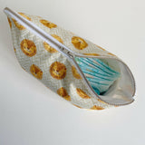 Nappy wallet in Leo lion print, partly unzipped at an angle with a stack of nappies showing through the opening