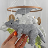 Little Dino Land felt cot mobile, hand holding the grey triceratops with cream horns, facing left