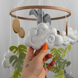 Little Dino Land felt cot mobile, hand holding a white felt cloud with grey swirl stitching