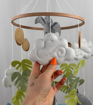 Little Dino Land felt cot mobile, hand holding a white felt cloud with grey swirl stitching