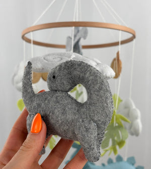 Little Dino Land felt cot mobile, hand holding the grey long-necked dinosaur from another angle, curved neck visible