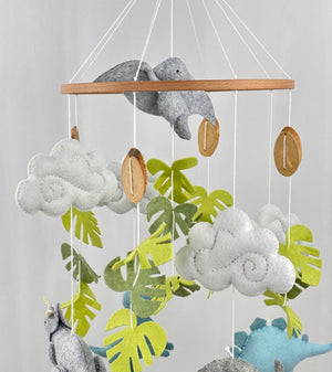 Little Dino Land felt cot mobile close-up of the upper ring, clouds, green leaves and wooden discs