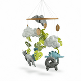 Little Dino Land felt cot mobile on a white background, showing dinosaurs, clouds and leaves hanging from a wooden ring