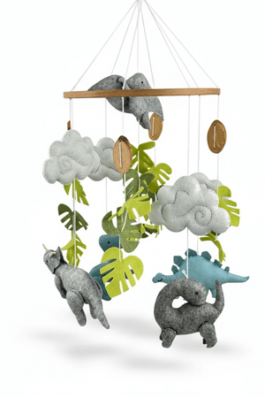 Little Dino Land felt cot mobile on a white background, showing dinosaurs, clouds and leaves hanging from a wooden ring