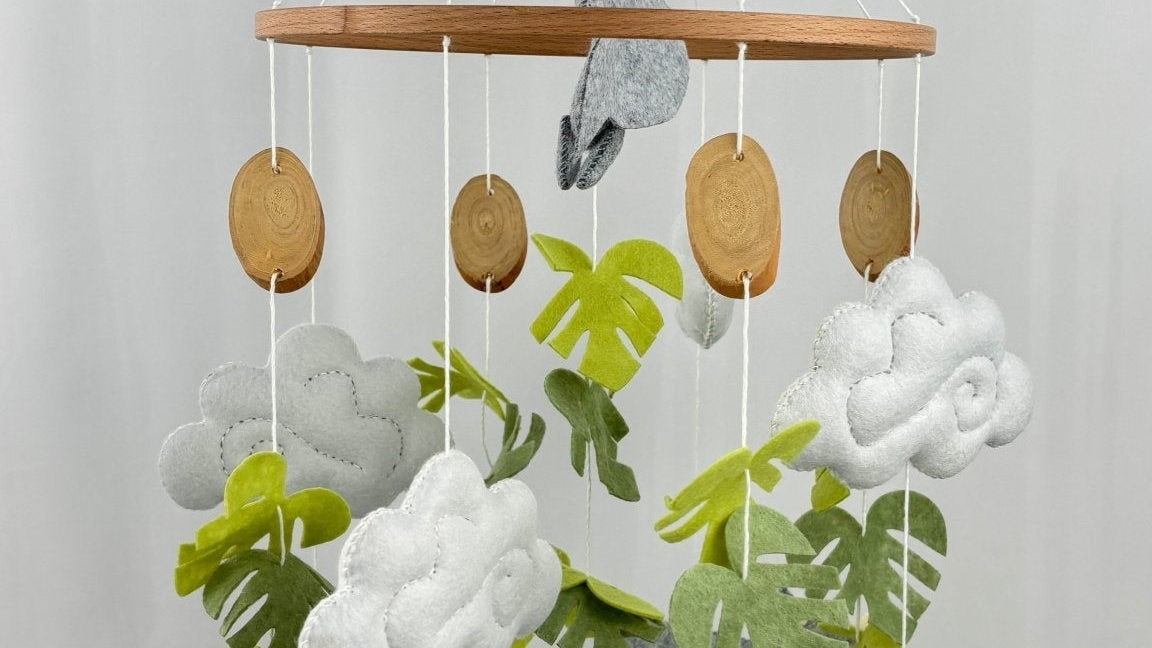 Little Dino Land felt cot mobile full view with hanging hook, wooden bead, slice-shaped discs and felt dinosaurs