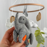 Little Dino Land felt cot mobile, hand holding the grey long-necked dinosaur, showing its side with stitched edges
