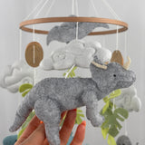 Little Dino Land felt cot mobile, hand holding the grey triceratops with cream horns, facing right