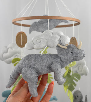 Little Dino Land felt cot mobile, hand holding the grey triceratops with cream horns, facing right