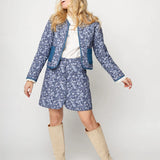 Woman wearing a blue floral outfit with beige boots on a white background
