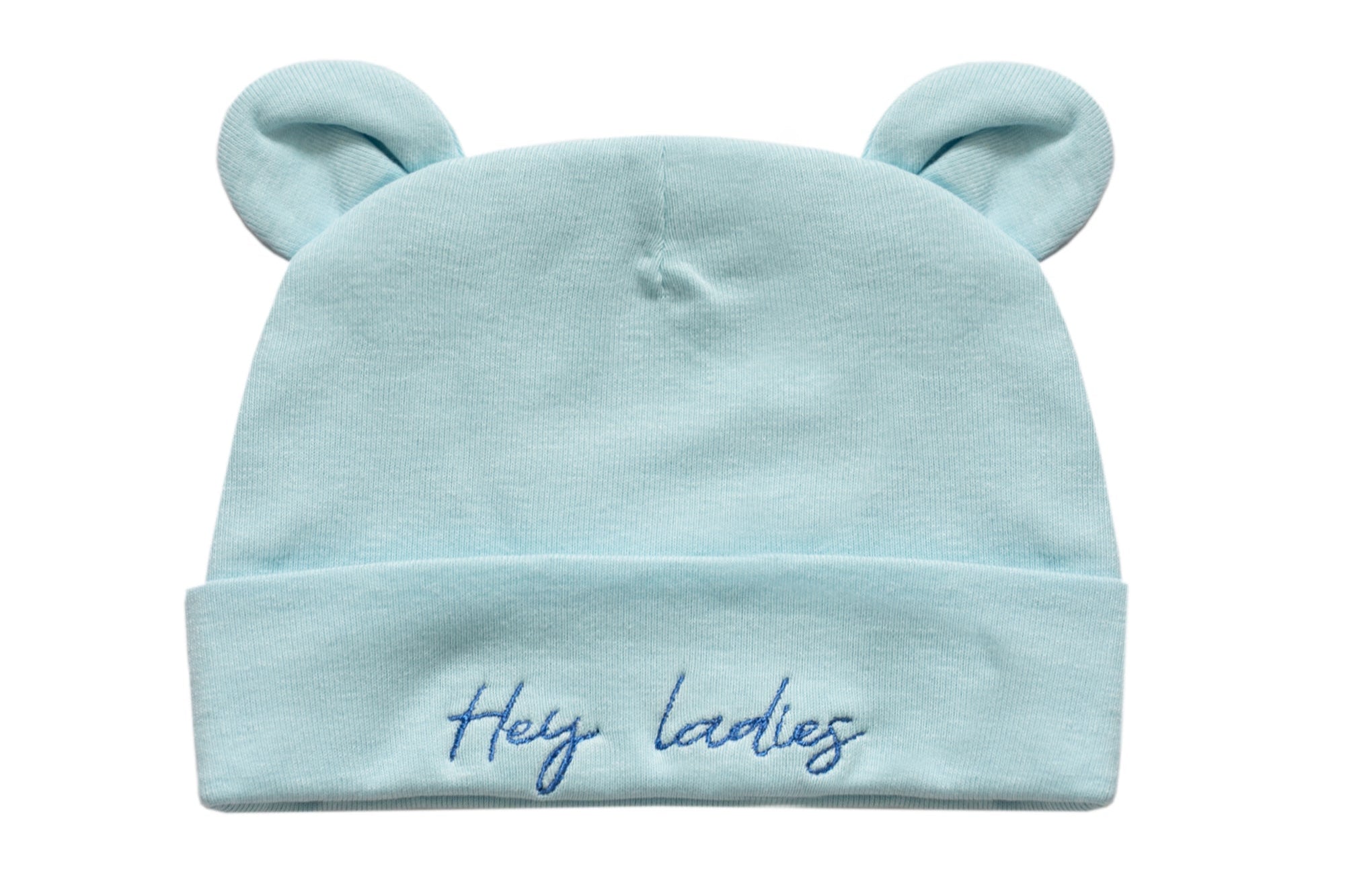 A light blue baby beanie hat with two small bear ears on top and the embroidered text 'Hey ladies' on the front cuff, shown against a plain white background.