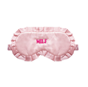 A light pink satin sleep mask with ruffled edges and the word 'MILF' embroidered in bright pink on the forehead, shown against a plain white background.