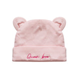 A light pink baby beanie hat with small bear ears on top and the words 'Queen bee' embroidered in pink script on the folded cuff, shown against a plain white background.