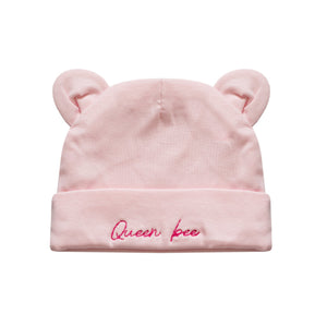 A light pink baby beanie hat with small bear ears on top and the words 'Queen bee' embroidered in pink script on the folded cuff, shown against a plain white background.