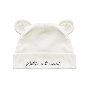 An off-white knit baby beanie hat featuring embroidered bear ears on top and the phrase 'Watch out world' in black script on the folded cuff.