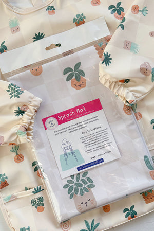 Splash Mat, Pot Plants: in its packaging laid on a matching plant print long-sleeved bib with elasticated cuffs