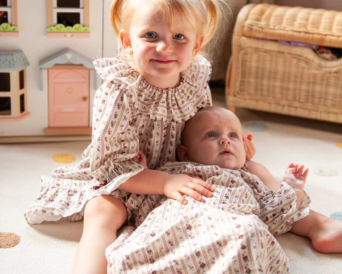 Beatrice Rose Stripe nightie, child sitting on a rug beside a baby, both wearing the floral striped nightie