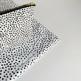 Nappy wallet in dalmatian print, corner of the pouch on the spotted mat with a handwritten brand name printed on it
