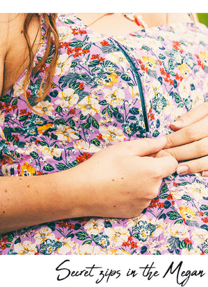 A close-up of a person wearing a floral-patterned dress with a visible black zipper running vertically. The dress has a purple base with multicolored flowers and green leaves.