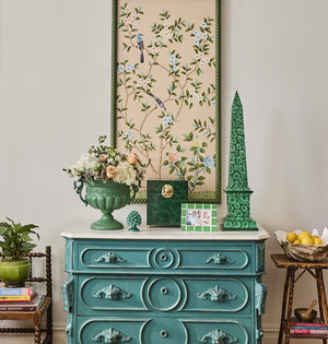 Mia Emerald Mosaic Photo Frame 6x4 on a teal chest of drawers with a green obelisk, urn of flowers and framed artwork