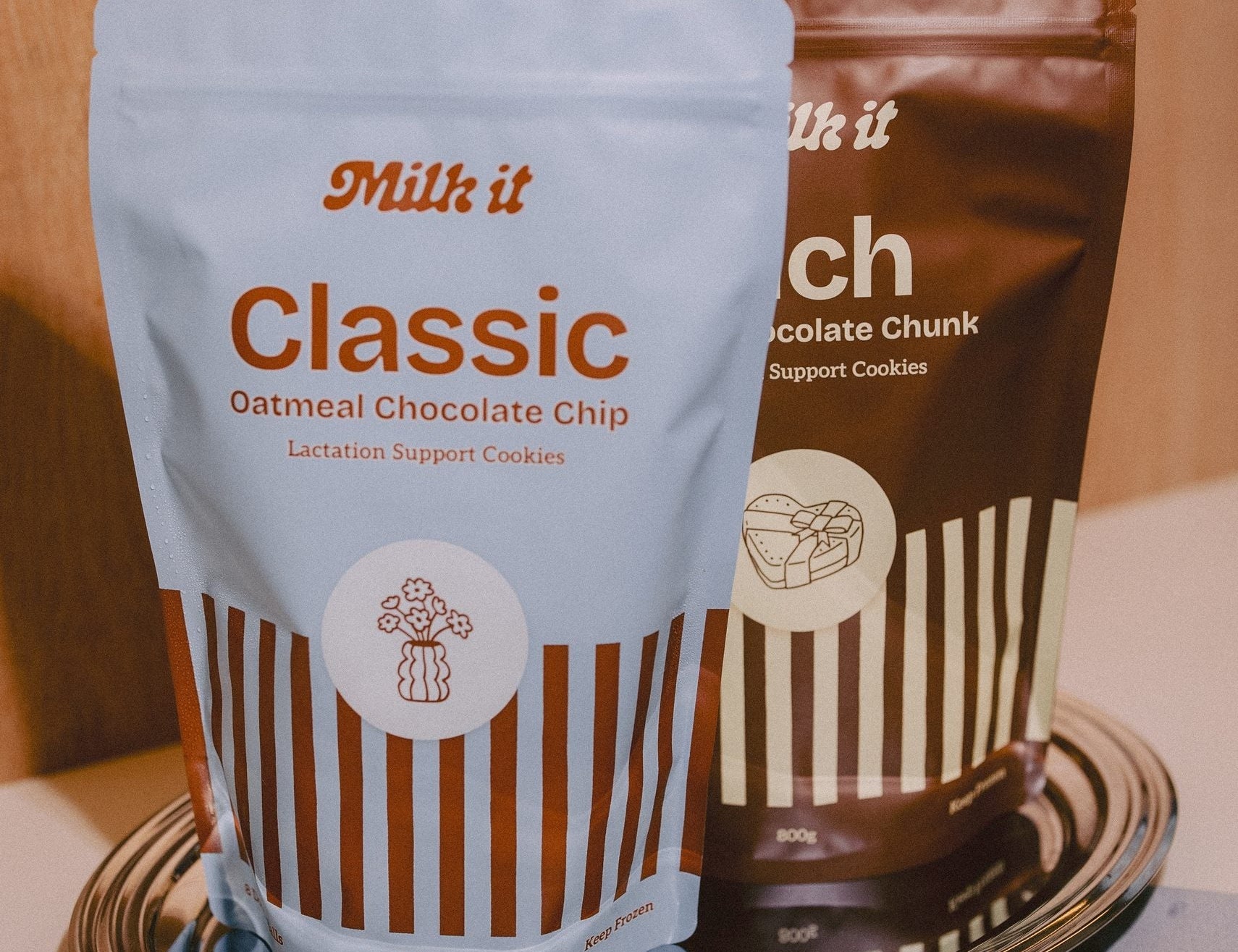 Milk it lactation cookie dough bundle: blue Classic and brown Rich pouches, 800g, standing together on a metal tray