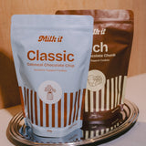 Milk it lactation cookie dough bundle: blue Classic and brown Rich pouches, 800g, standing together on a metal tray