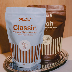 Milk it lactation cookie dough bundle: blue Classic and brown Rich pouches, 800g, standing together on a metal tray