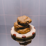 Milk it cookie dough bundle: stack of three baked oatmeal chocolate chip cookies on a cream dish with brown spots