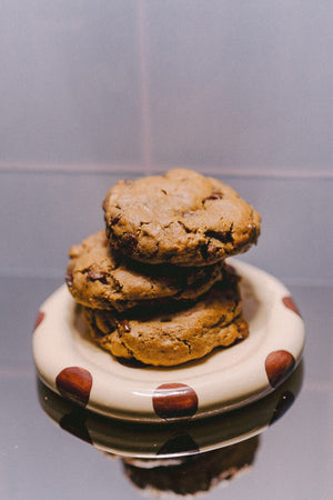 Milk it cookie dough bundle: stack of three baked oatmeal chocolate chip cookies on a cream dish with brown spots