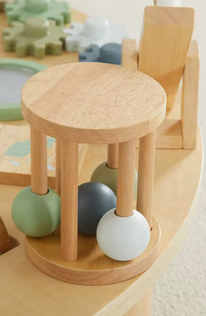 Wooden activity table, natural: close-up of the round wooden rattle drum with green, grey and white balls inside