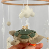 Ocean Whispers felt cot mobile detail of the felt turtle with green shell patches held in a hand