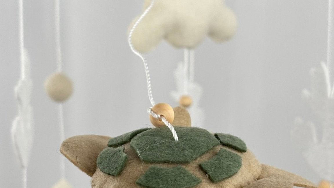 Ocean Whispers felt cot mobile detail of the felt turtle with green shell patches held in a hand