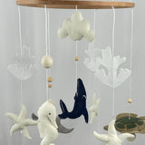 Ocean Whispers felt cot mobile showing a white seahorse, cloud, starfish and coral hanging beneath the wooden ring