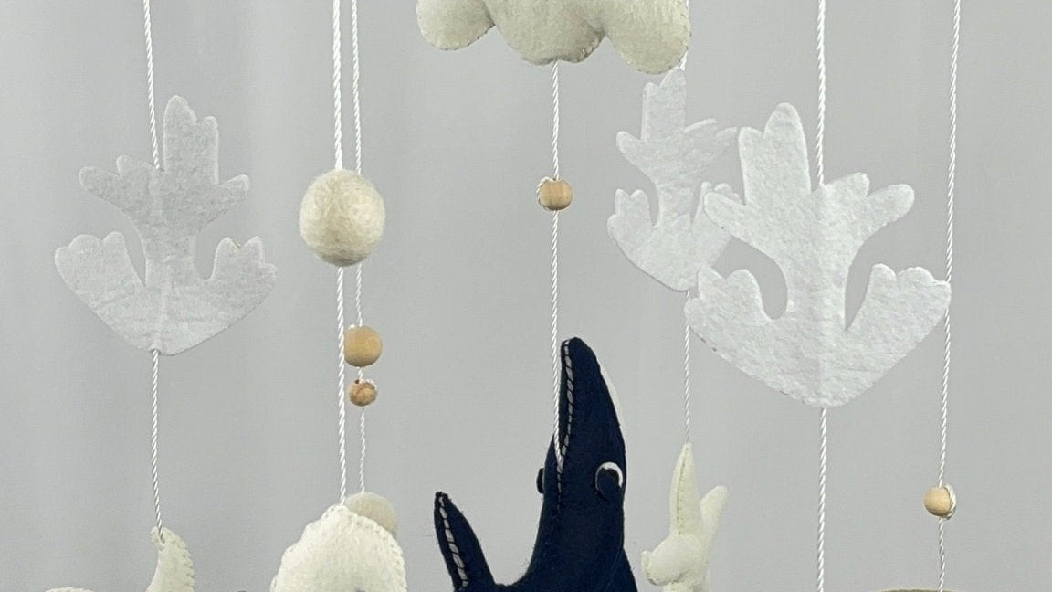 Ocean Whispers felt cot mobile showing a white seahorse, cloud, starfish and coral hanging beneath the wooden ring