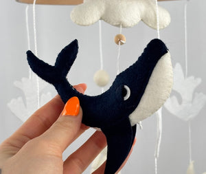 Ocean Whispers felt cot mobile detail of the navy and cream felt whale held in a hand