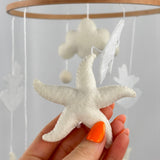 Ocean Whispers felt cot mobile detail of a cream felt starfish with visible stitching held in a hand