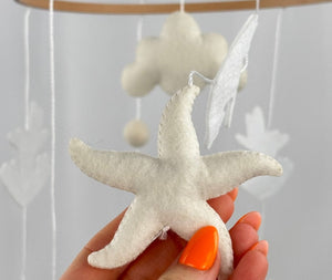 Ocean Whispers felt cot mobile detail of a cream felt starfish with visible stitching held in a hand