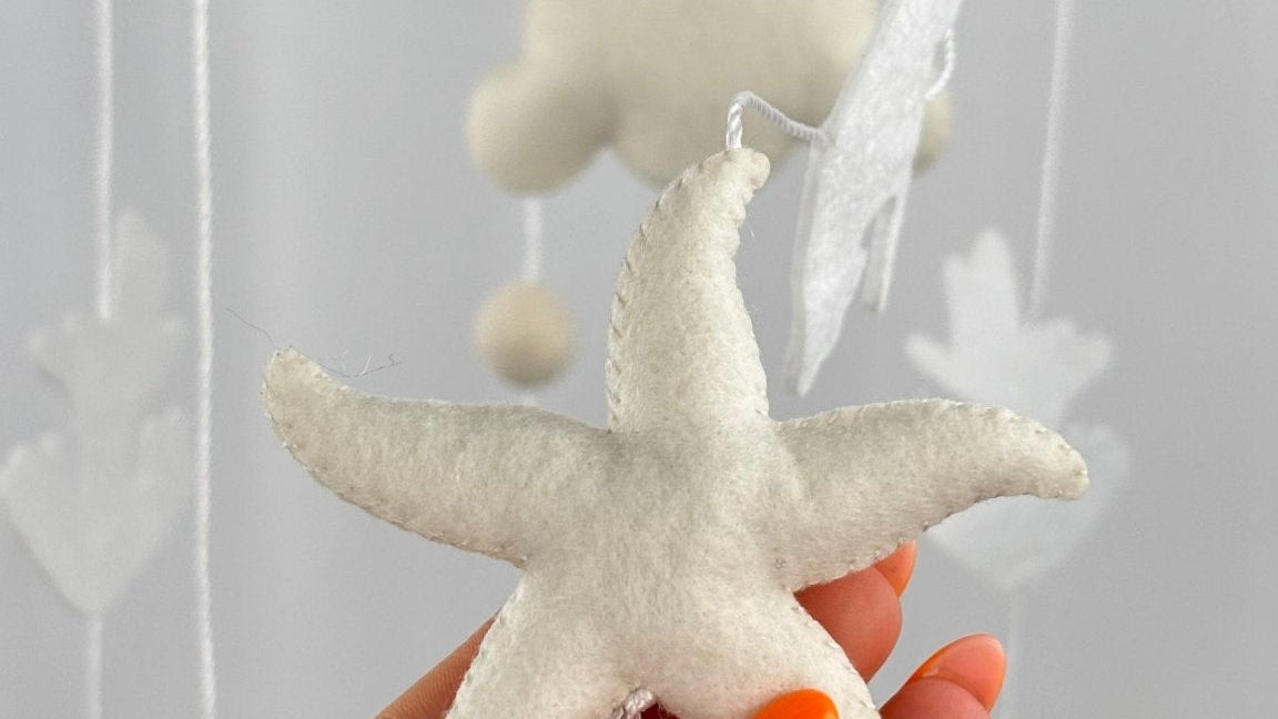 Ocean Whispers felt cot mobile detail of a cream felt starfish with visible stitching held in a hand