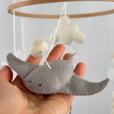 Ocean Whispers felt cot mobile detail of the grey felt stingray with a felt ball above, resting on a hand