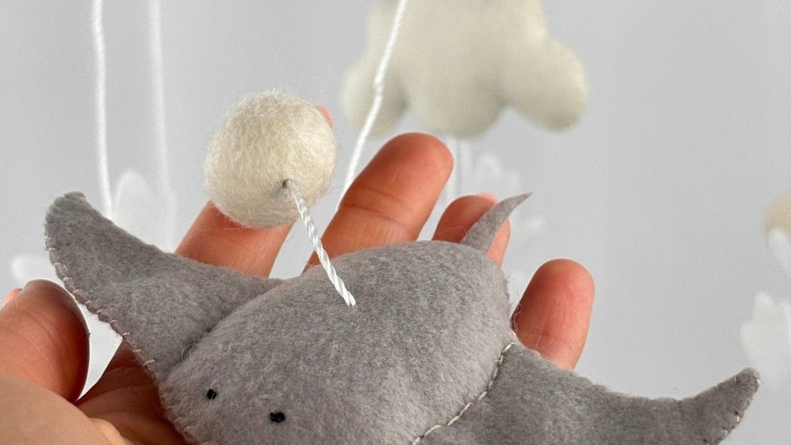 Ocean Whispers felt cot mobile detail of the grey felt stingray with a felt ball above, resting on a hand
