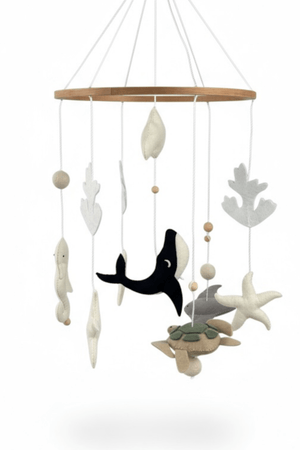 Ocean Whispers felt cot mobile on a white background, wooden ring with whale, turtle, stingray, starfish and coral