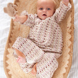 Beatrice Rose Stripe baby nightie, baby lying in a woven basket with arms raised, holding a soft toy
