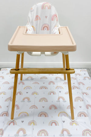 Splash Mat Beau Pink Rainbow Print laid on carpet under a wooden high chair with a pink tray and matching seat cushion