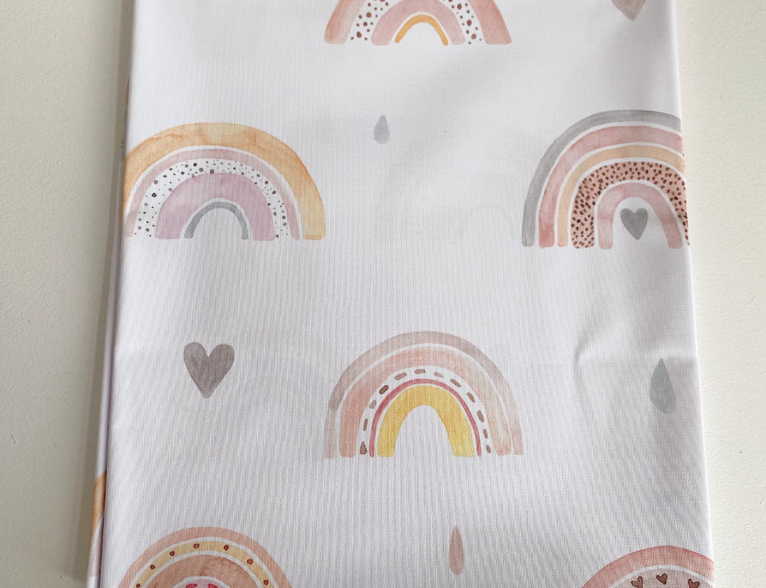 Splash Mat Beau Pink Rainbow Print, folded flat showing a pattern of pink and yellow rainbows, hearts and raindrops