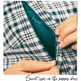 Close-up of a person's hands opening a dark teal zipper on a blue and white plaid garment, with the text 'Secret zips in the poppy dress' at the bottom.