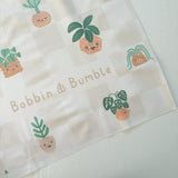 Splash Mat, Pot Plants: corner close-up showing the smiling plant pot print on a beige checkerboard background